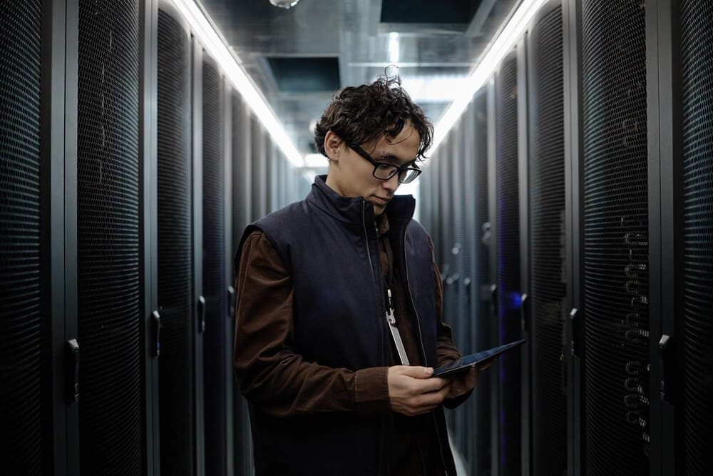 Técnico asiático usando tablet no corredor de data center moderno