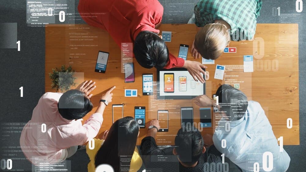 Visão aérea de equipe em brainstorming com tablet e programa de código