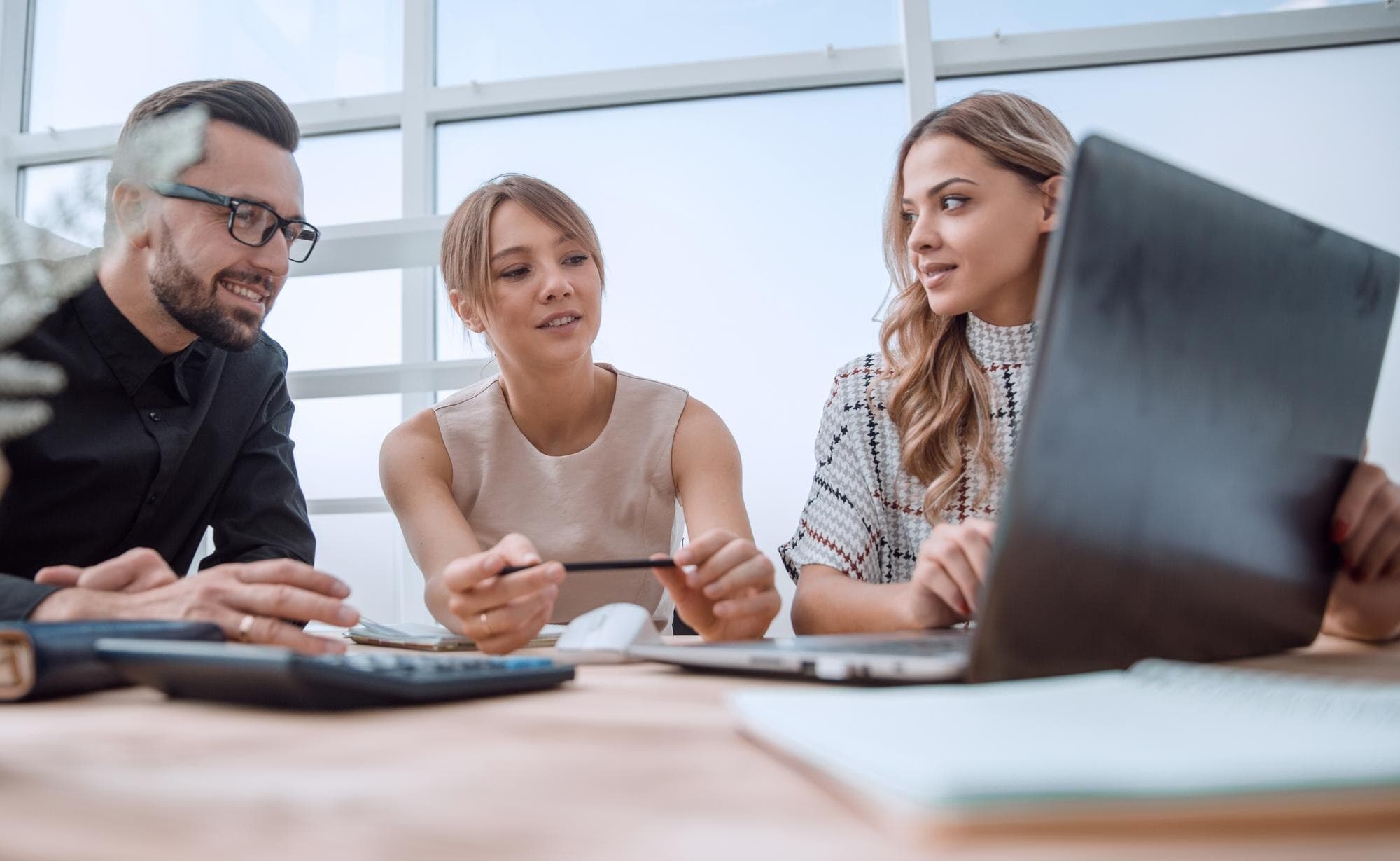 Equipe discutindo um projeto em torno de documentos e notebook