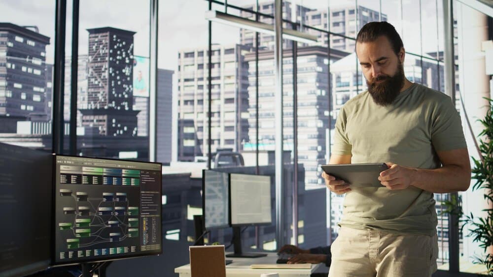 Programador desenvolvendo APIs e verificando performance em tablet no escritório