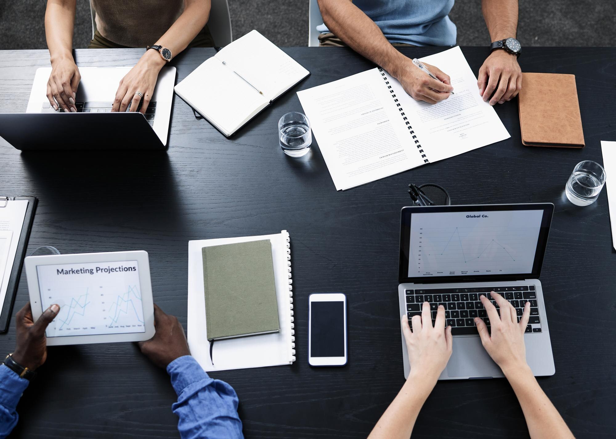 Equipe colaborando em torno de uma mesa com notebook e documentos